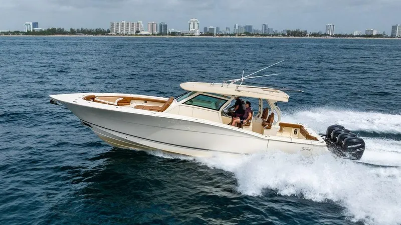  Yacht Photos Pics 2018 Scout 420 LXF boat cruising on ocean near city skyline.