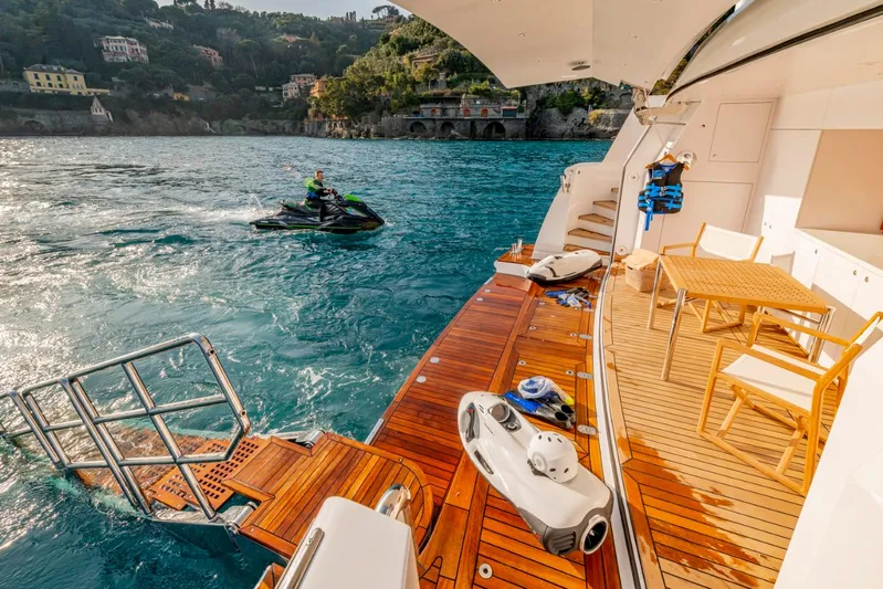  Yacht Photos Pics Luxurious Heesen 38m yacht deck with jet ski, wooden furniture, and scenic coastal view.