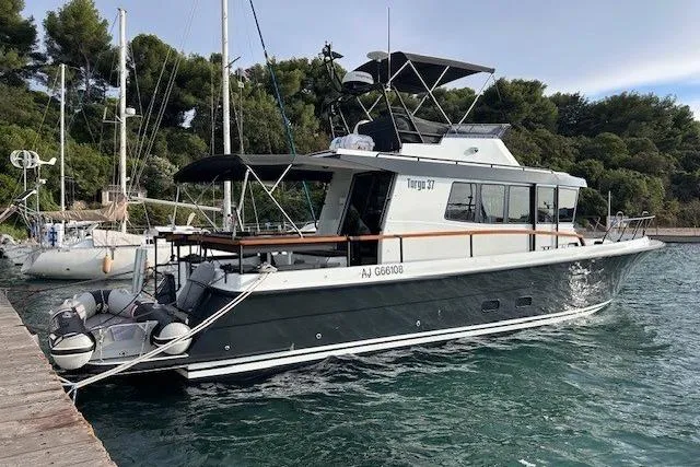  Yacht Photos Pics 2022 Botnia Targa 37 boat docked in a marina, surrounded by trees.