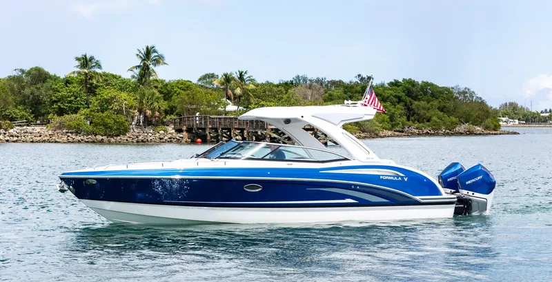  Yacht Photos Pics 2024 Formula 310 BR boat cruising on a scenic waterway with lush greenery.