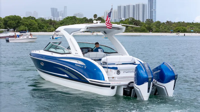  Yacht Photos Pics 2024 Formula 310 BR boat cruising near a city skyline and beach.