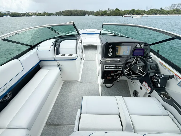  Yacht Photos Pics 2024 Formula 310 BR boat interior with modern dashboard and seating, on a scenic waterway.