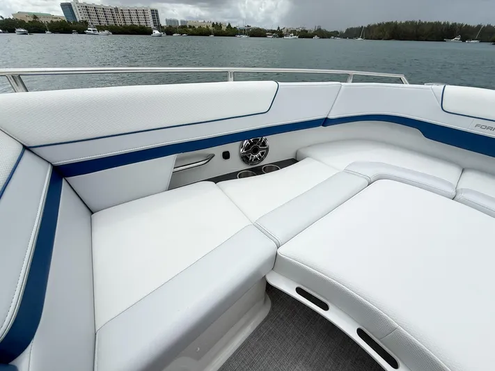  Yacht Photos Pics 2024 Formula 310 BR boat interior with white and blue seating, on a calm waterfront.