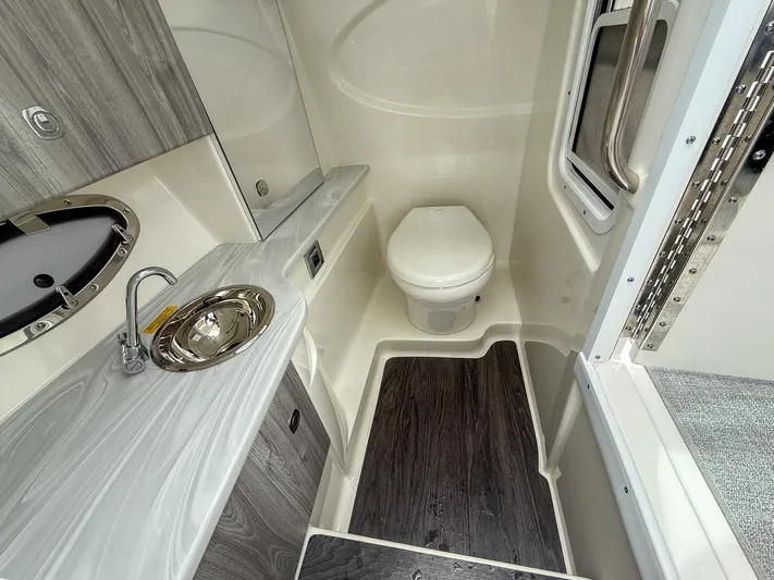  Yacht Photos Pics 2024 Formula 310 BR boat bathroom with sink, toilet, and wood accents.