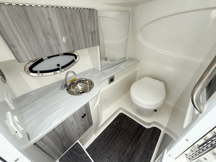  Yacht Photos Pics 2024 Formula 310 BR boat bathroom with modern sink, toilet, and wood accents.