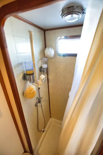 Funky Monkey Yacht Photos Pics Compact boat shower with beige tiles, wooden trim, and a small window on a 2001 Monk 36.