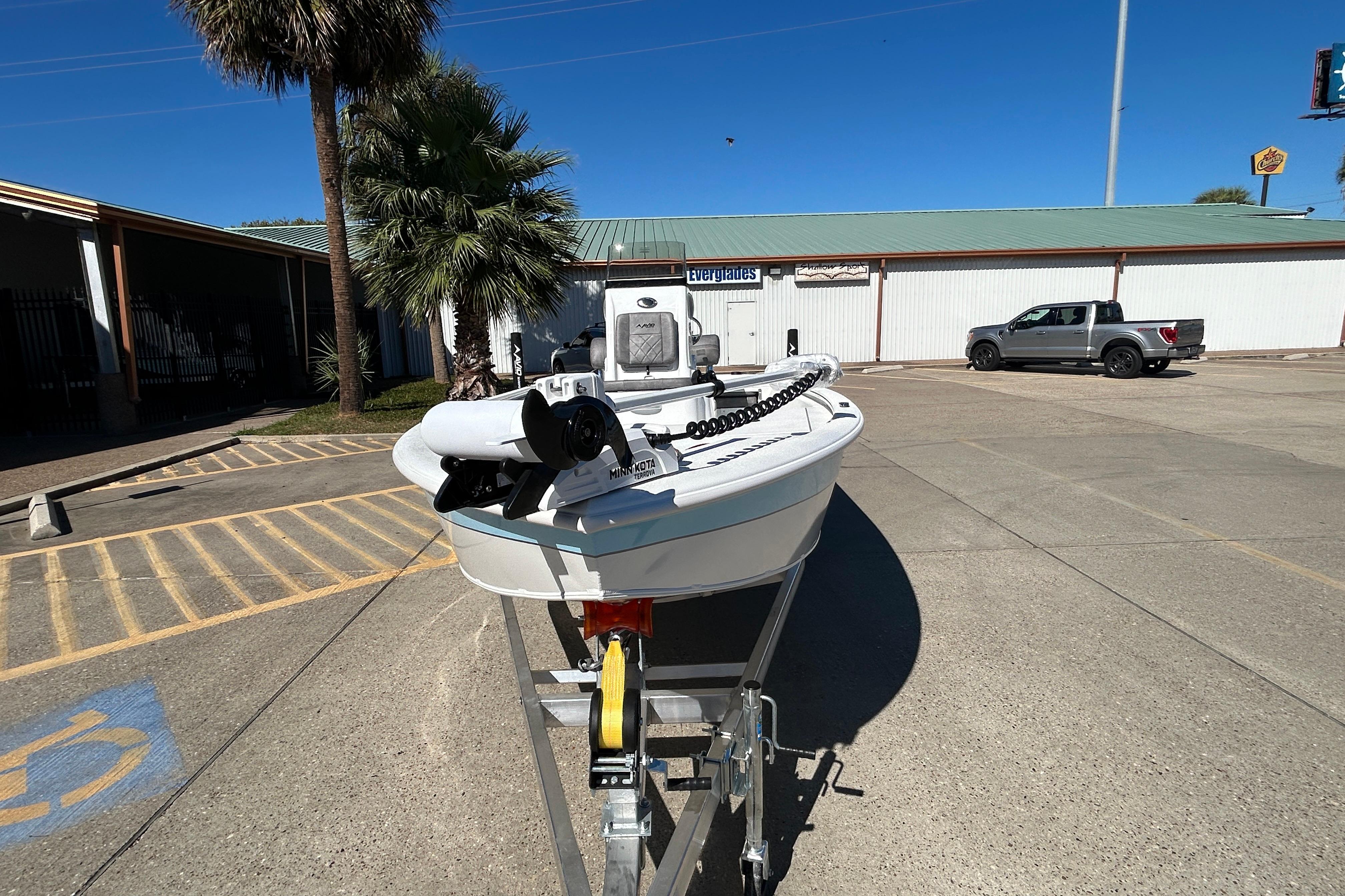 2025 Avid 21 FST boat on trailer in parking lot, palm tree nearby.
