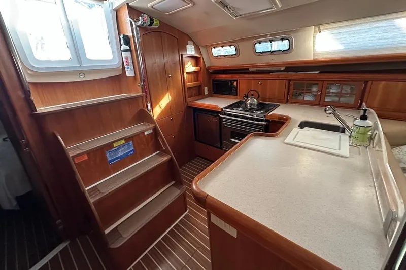 Free Range Yacht Photos Pics Interior of 2005 Hunter 44 sailboat kitchen with wooden cabinetry and modern appliances.