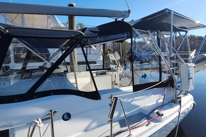 Free Range Yacht Photos Pics 2005 Hunter 44 sailboat with cockpit enclosure and solar panels, docked in a marina.
