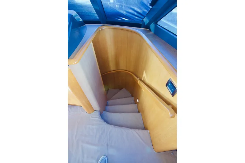 T.t. Amore Yacht Photos Pics Staircase in 2004 West Bay Cockpit Pilot House Motoryacht, featuring wooden handrails and carpeted steps.