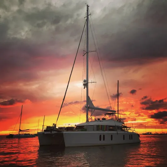 Chasing Waterfalls Yacht Photos Pics Sailing yacht Tayana Isara 50 at sunset, 2014 model, silhouetted against vibrant sky.