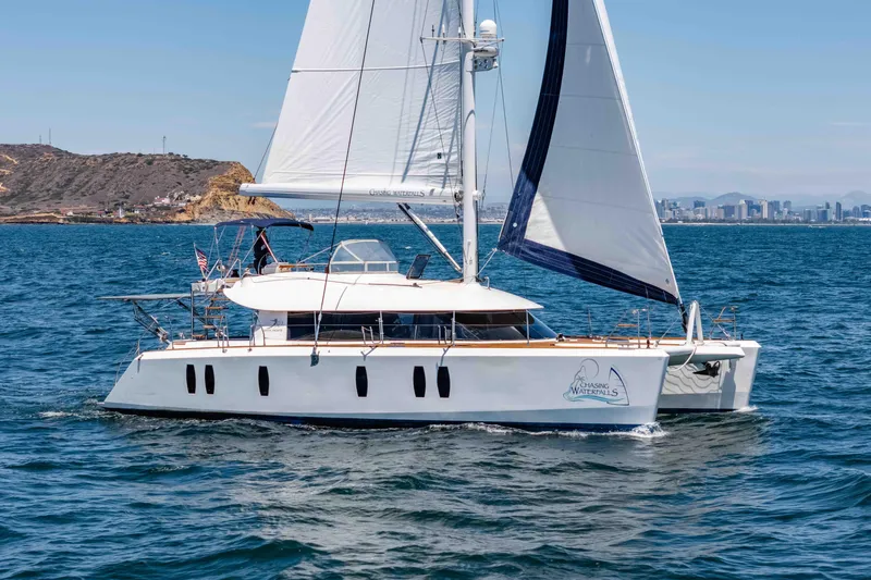 Chasing Waterfalls Yacht Photos Pics Sailing catamaran Tayana Isara 50, 2014 model, cruising on open water with city skyline backdrop.