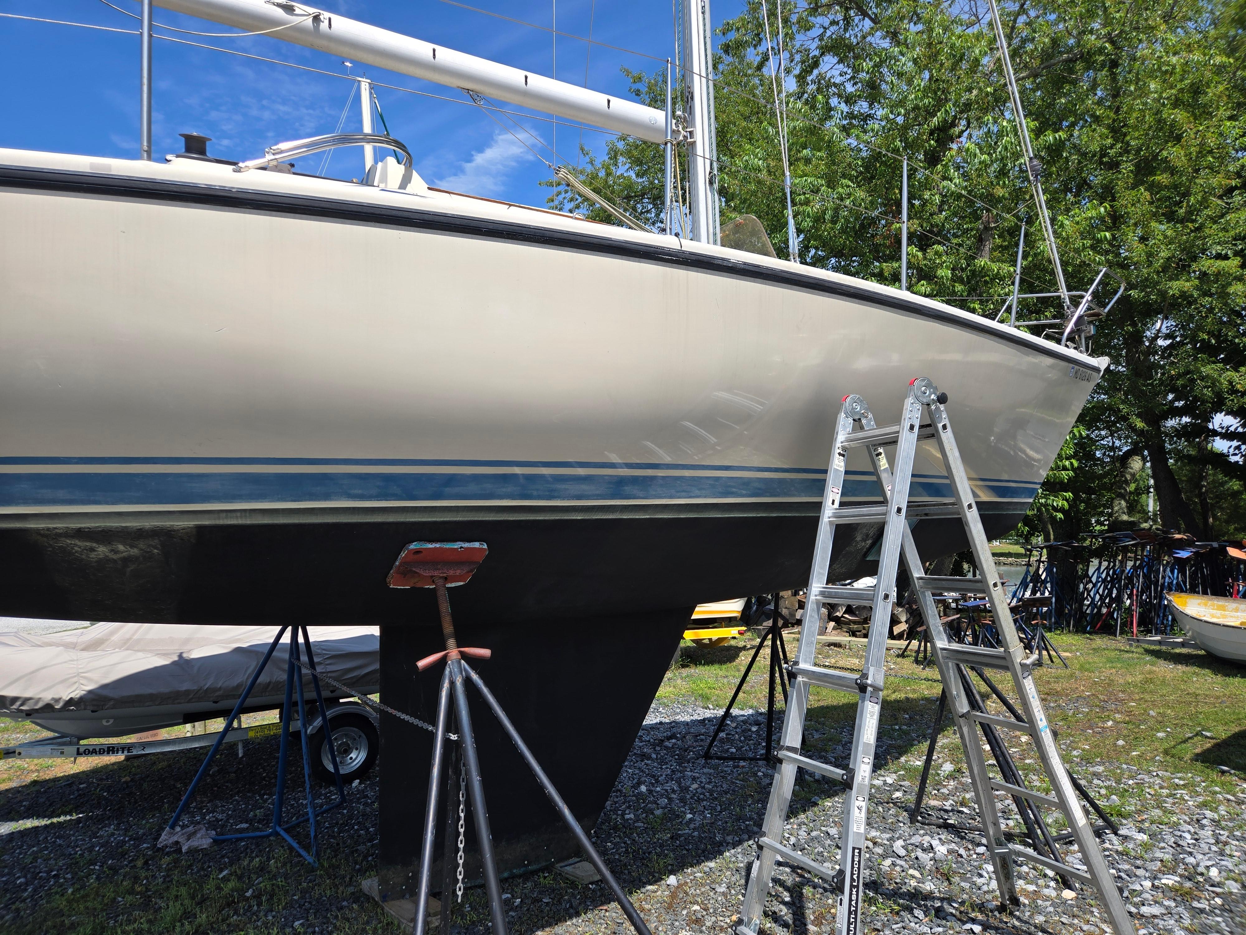 1987 Dehler Optima 34 sailboat on land, supported by stands and ladder.