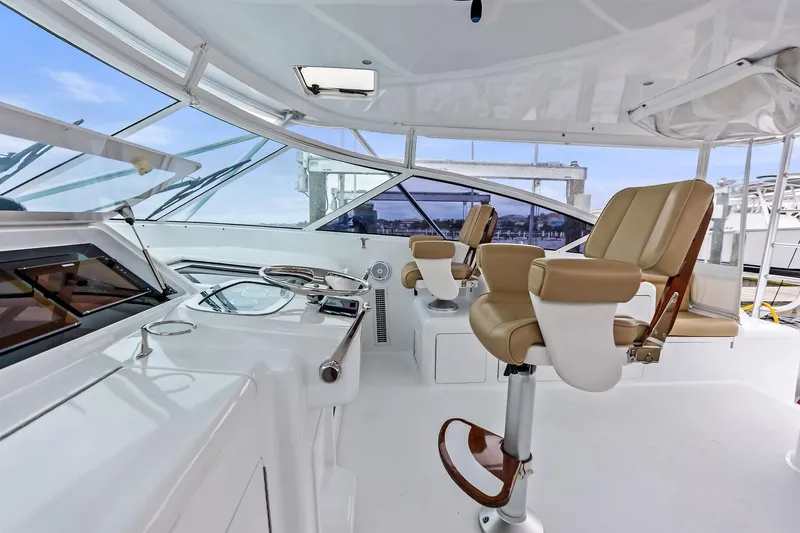 Urgent Sea Yacht Photos Pics 2003 Viking 45 Open yacht helm with beige captain chairs and panoramic windows.