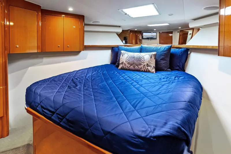 Urgent Sea Yacht Photos Pics Luxurious cabin interior of 2003 Viking 45 Open yacht with blue bedding and wooden cabinets.