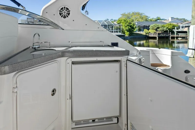 Yaeli Yacht Photos Pics 2005 Regal Commodore 3560 yacht kitchenette with sink and storage, docked by waterfront homes.