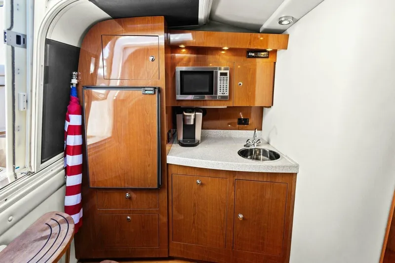 Yaeli Yacht Photos Pics 2005 Regal Commodore 3560 yacht kitchenette with microwave, sink, and wooden cabinetry.
