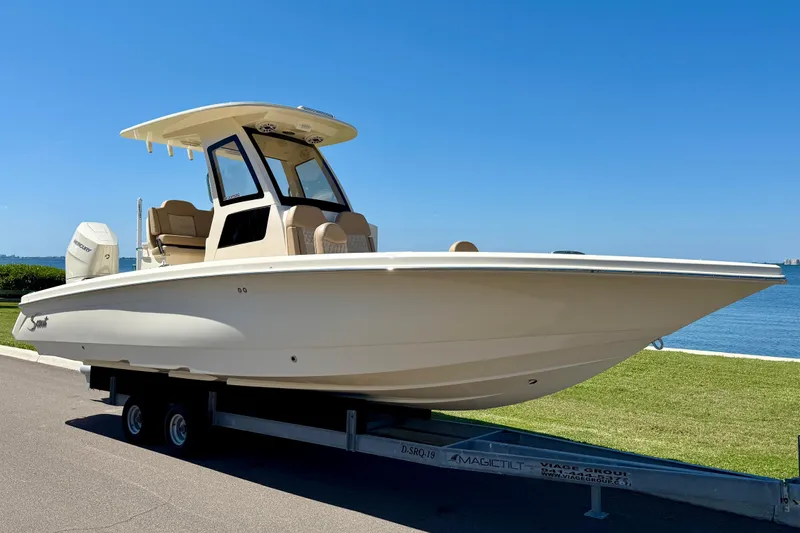  Yacht Photos Pics 2025 Scout 261 XSS boat on trailer by waterfront, clear blue sky.