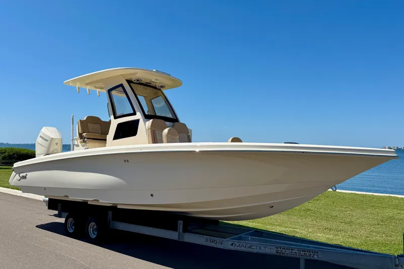  Yacht Photos Pics 2025 Scout 261 XSS boat on trailer by waterfront, clear blue sky.