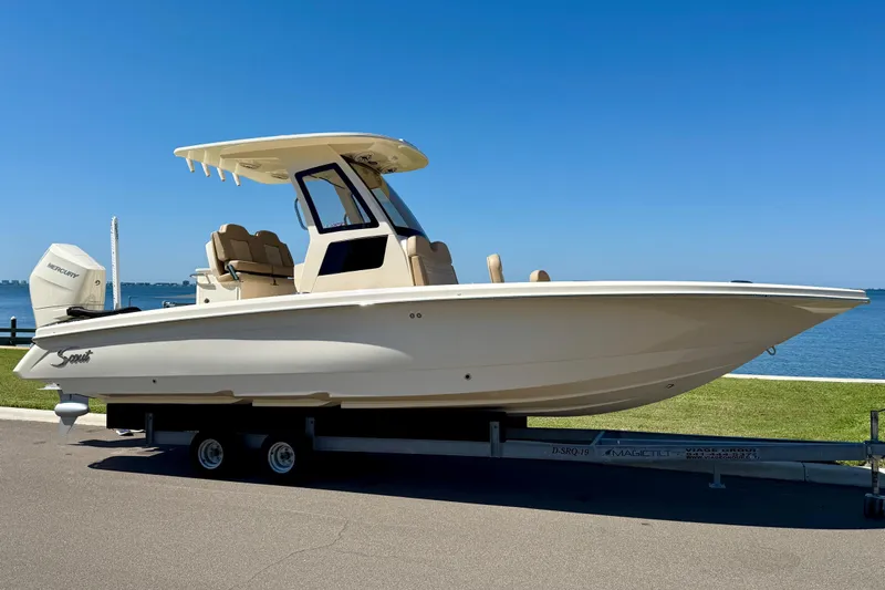 Yacht Photos Pics 2025 Scout 261 XSS boat on trailer by waterfront, clear blue sky background.