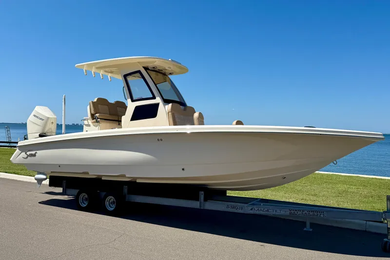  Yacht Photos Pics 2025 Scout 261 XSS boat on trailer by the waterfront under clear blue sky.