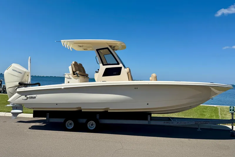  Yacht Photos Pics 2025 Scout 261 XSS boat on trailer by the waterfront under clear blue sky.