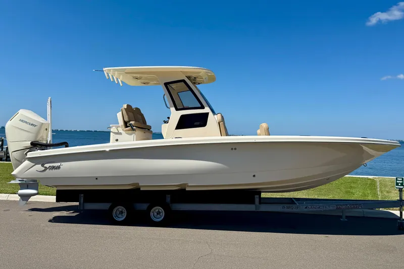  Yacht Photos Pics 2025 Scout 261 XSS boat on trailer by waterfront, clear blue sky.