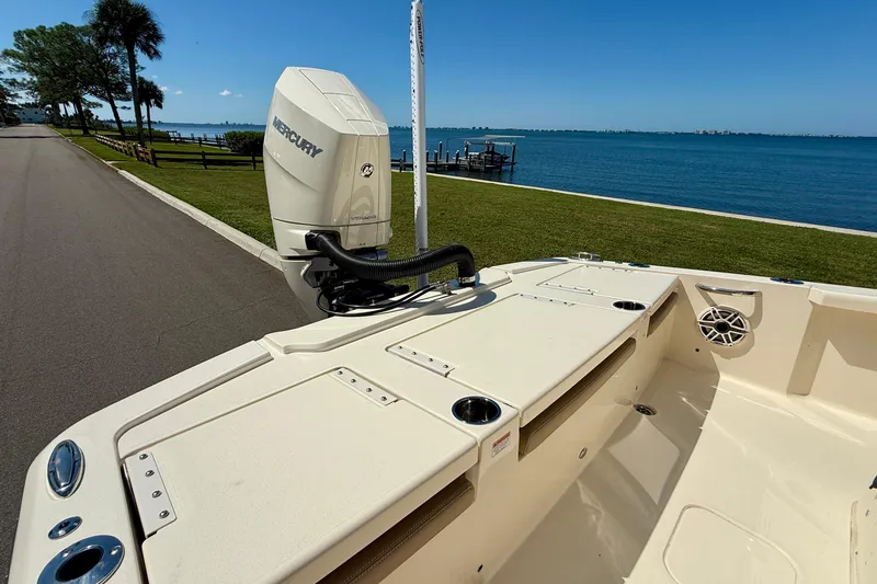  Yacht Photos Pics 2025 Scout 261 XSS boat with Mercury engine by a scenic waterfront.