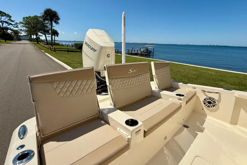  Yacht Photos Pics 2025 Scout 261 XSS boat interior with beige seating, near a scenic waterfront.