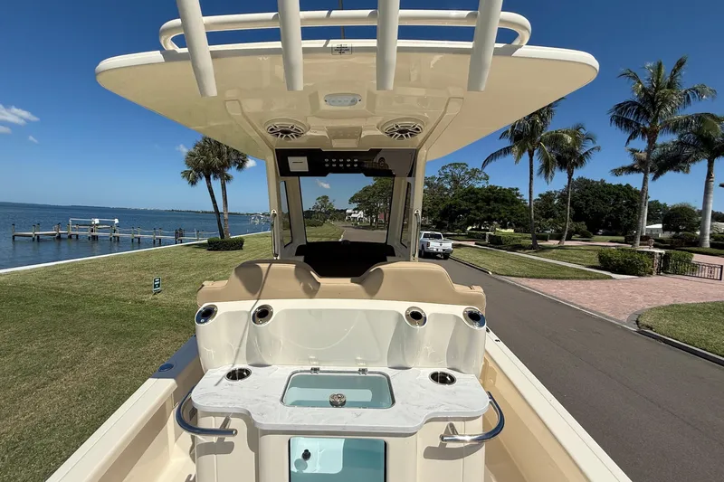  Yacht Photos Pics 2025 Scout 261 XSS boat with sleek design, docked near waterfront, palm trees in background.