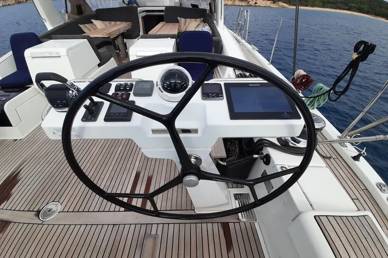  Yacht Photos Pics Steering wheel and controls of a 2015 Jeanneau Yachts 64 on a wooden deck.