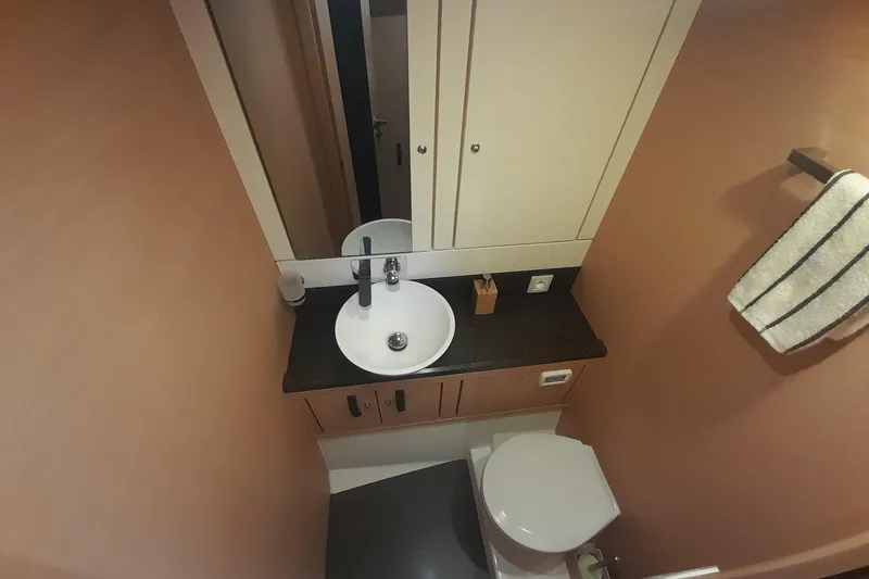  Yacht Photos Pics Bathroom interior of 2015 Jeanneau Yachts 64, featuring sink, mirror, and toilet.