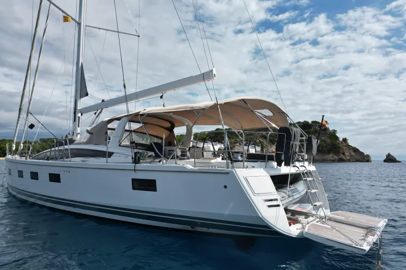  Yacht Photos Pics 2015 Jeanneau Yachts 64 sailing on calm waters near a rocky coastline.