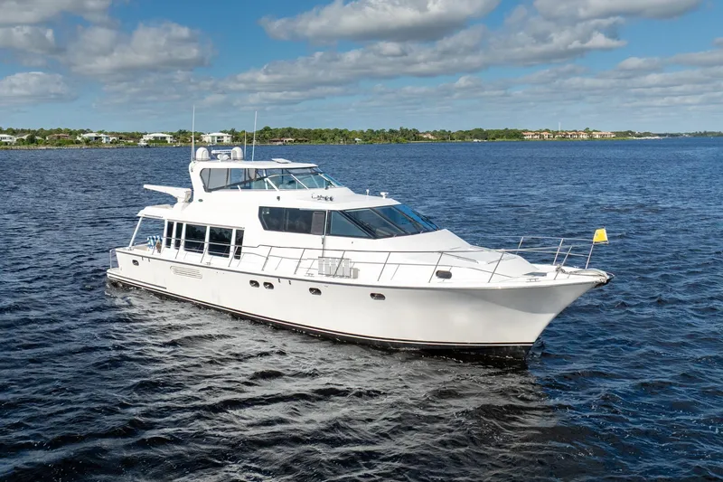 Last Call Yacht Photos Pics 2009 Pacific Mariner 65 Motoryacht cruising on a serene blue lake under a partly cloudy sky.