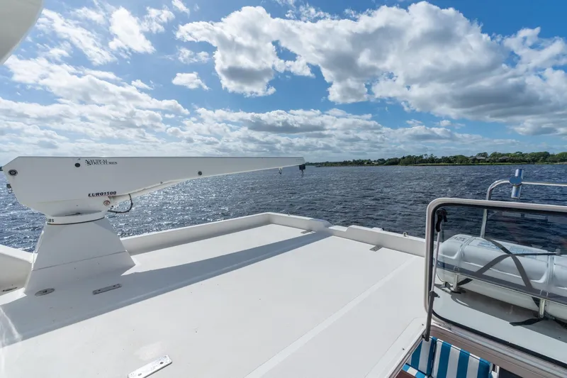 Last Call Yacht Photos Pics 2009 Pacific Mariner 65 Motoryacht deck with crane, overlooking serene water and sky.