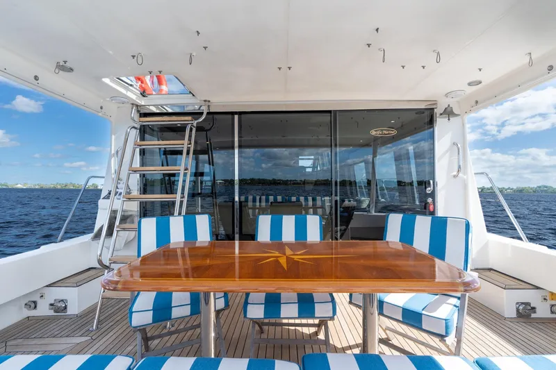 Last Call Yacht Photos Pics 2009 Pacific Mariner 65 Motoryacht deck with striped seating and wooden table, ocean view.