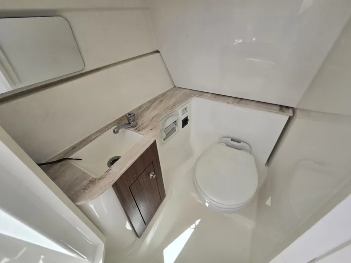  Yacht Photos Pics 2020 Pursuit 266 boat bathroom with sink, toilet, and mirror.