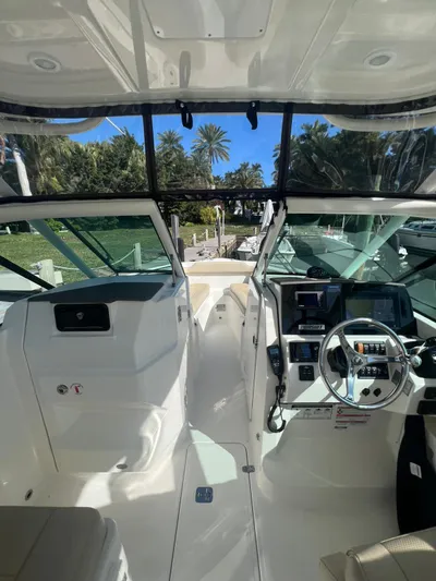  Yacht Photos Pics 2020 Pursuit 266 boat interior with steering wheel and dashboard, docked near palm trees.