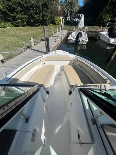  Yacht Photos Pics 2020 Pursuit 266 boat docked by lush greenery and calm water.