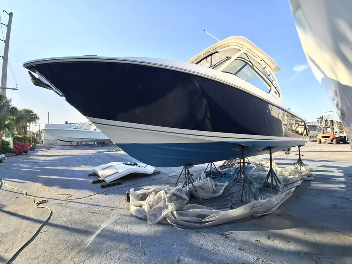  Yacht Photos Pics 2020 Pursuit 266 boat on stands, blue hull, outdoor setting.