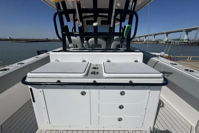 The Madd House Yacht Photos Pics 2023 Twin Vee 400 GFX CC boat interior with seating and storage, docked by a bridge.