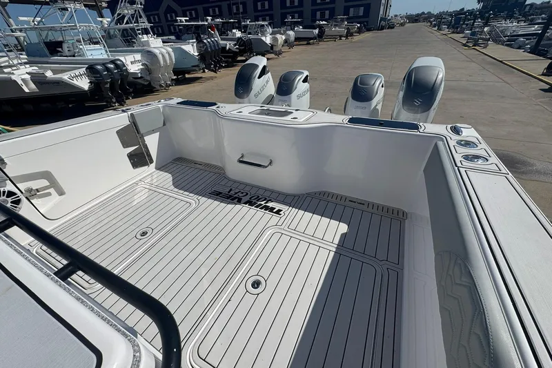 The Madd House Yacht Photos Pics 2023 Twin Vee 400 GFX CC boat deck with Suzuki outboard engines at a marina.
