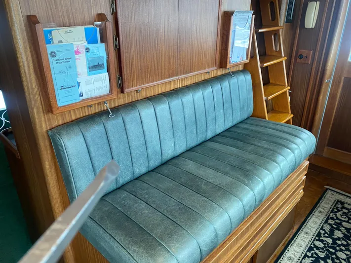  Yacht Photos Pics 1983 Hatteras 53 Motor Yacht interior with blue cushioned bench and wooden accents.