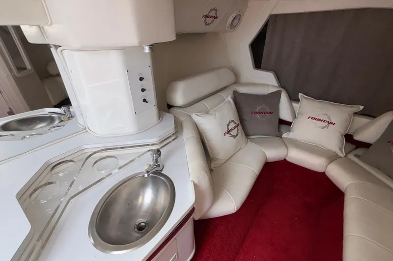  Yacht Photos Pics 2007 Fountain 38 Lightning interior with white seating, red carpet, and stainless steel sink.