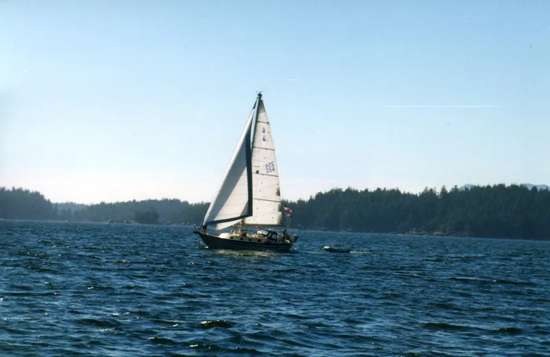 Sapphire Yacht Photos Pics Sailboat Pacific Seacraft 37, 1992 model, cruising on a serene lake with forested shoreline.