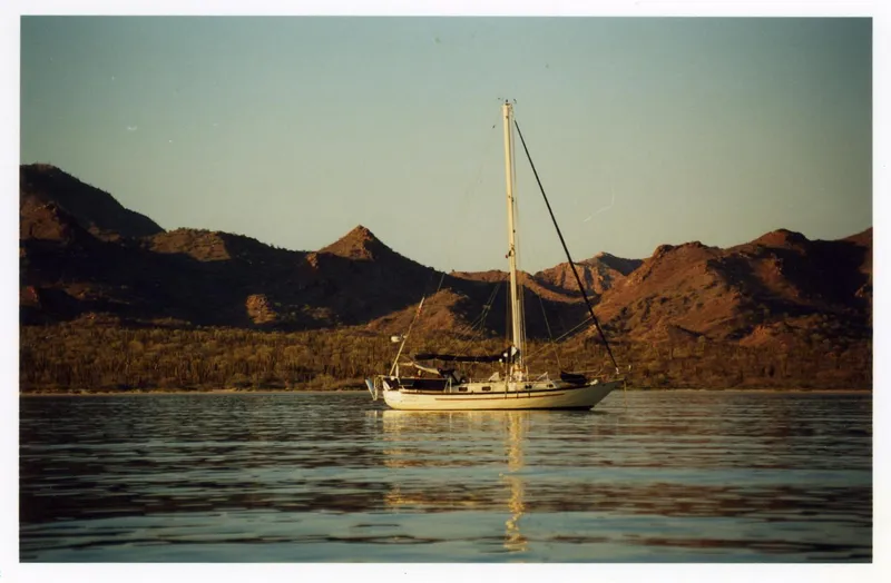 Sapphire Yacht Photos Pics Sailboat Pacific Seacraft 37, 1992 model, on calm water with mountainous backdrop.