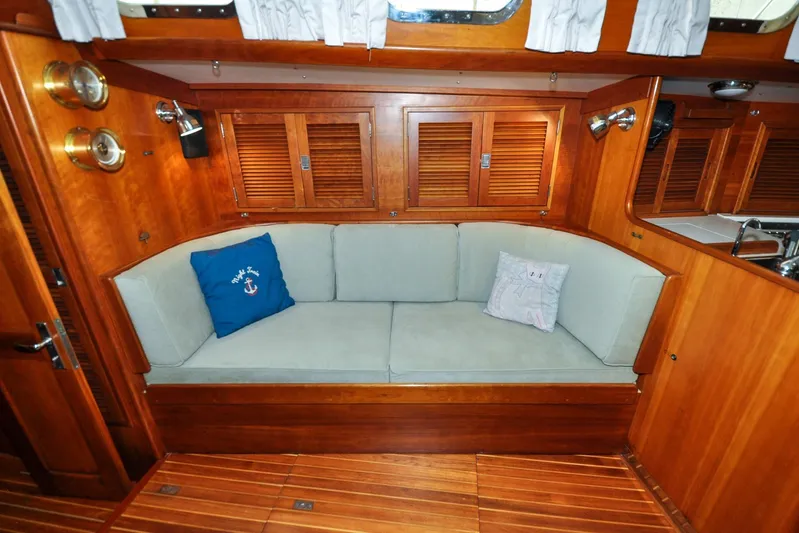 Night Train Yacht Photos Pics Cozy interior of 1986 Hinckley Sou'wester 51 sailboat with wooden finish and cushioned seating.