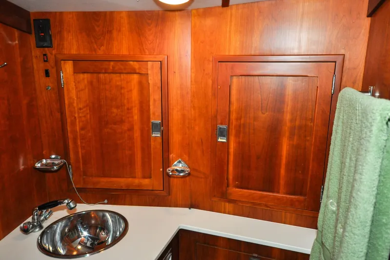Night Train Yacht Photos Pics 1986 Hinckley Sou'wester 51 yacht bathroom with wooden cabinets and stainless steel sink.