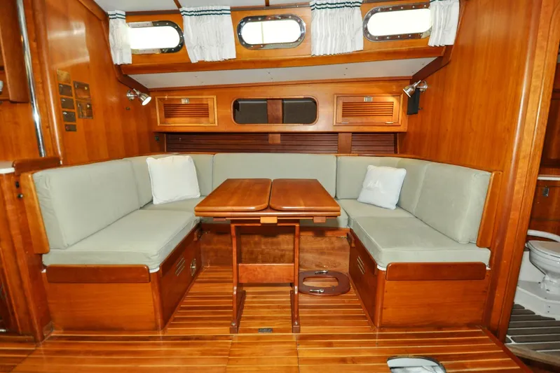Night Train Yacht Photos Pics Interior of 1986 Hinckley Sou'wester 51 sailboat with wooden dining area and cushioned seating.