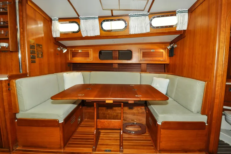 Night Train Yacht Photos Pics Interior of 1986 Hinckley Sou'wester 51 sailboat with wooden dining area and cushioned seating.